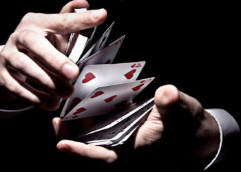 Manos barajando cartas sobre fondo negro